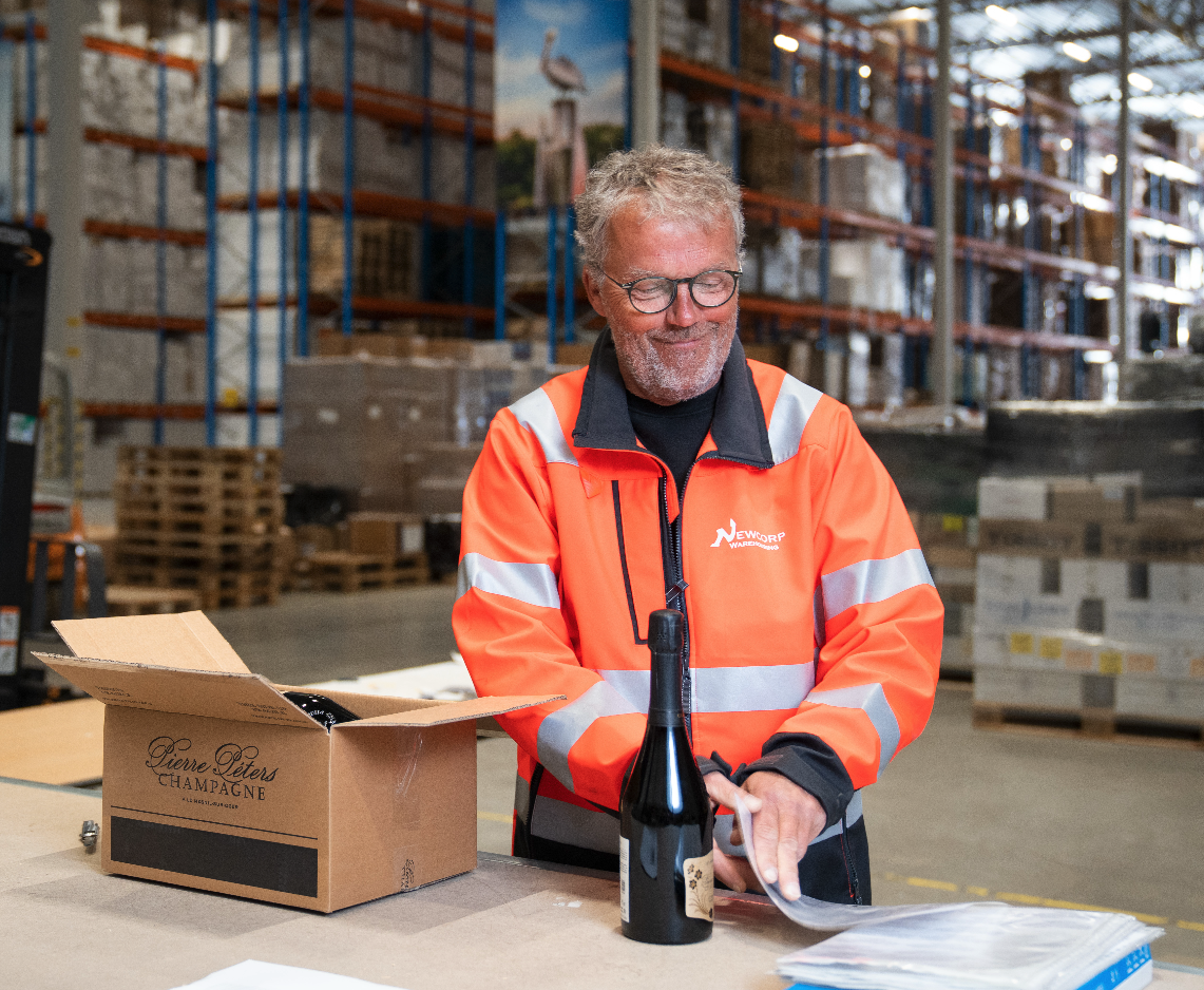 Medewerker is in het warehouse wijn aan het verpakken
